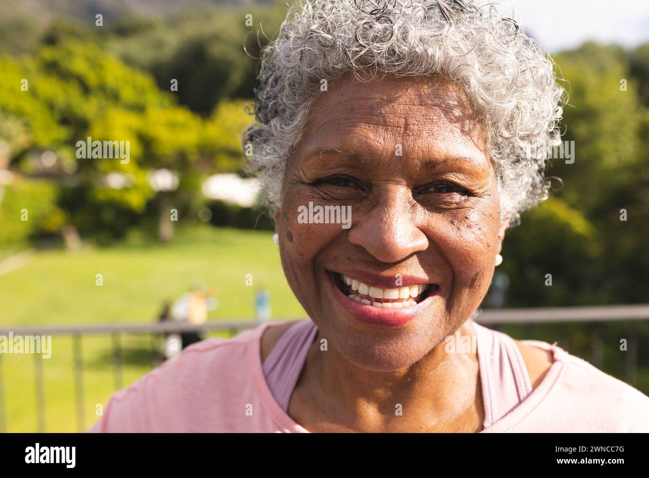 Senior biracial woman with curly gray hair smiles warmly outdoors Stock ...