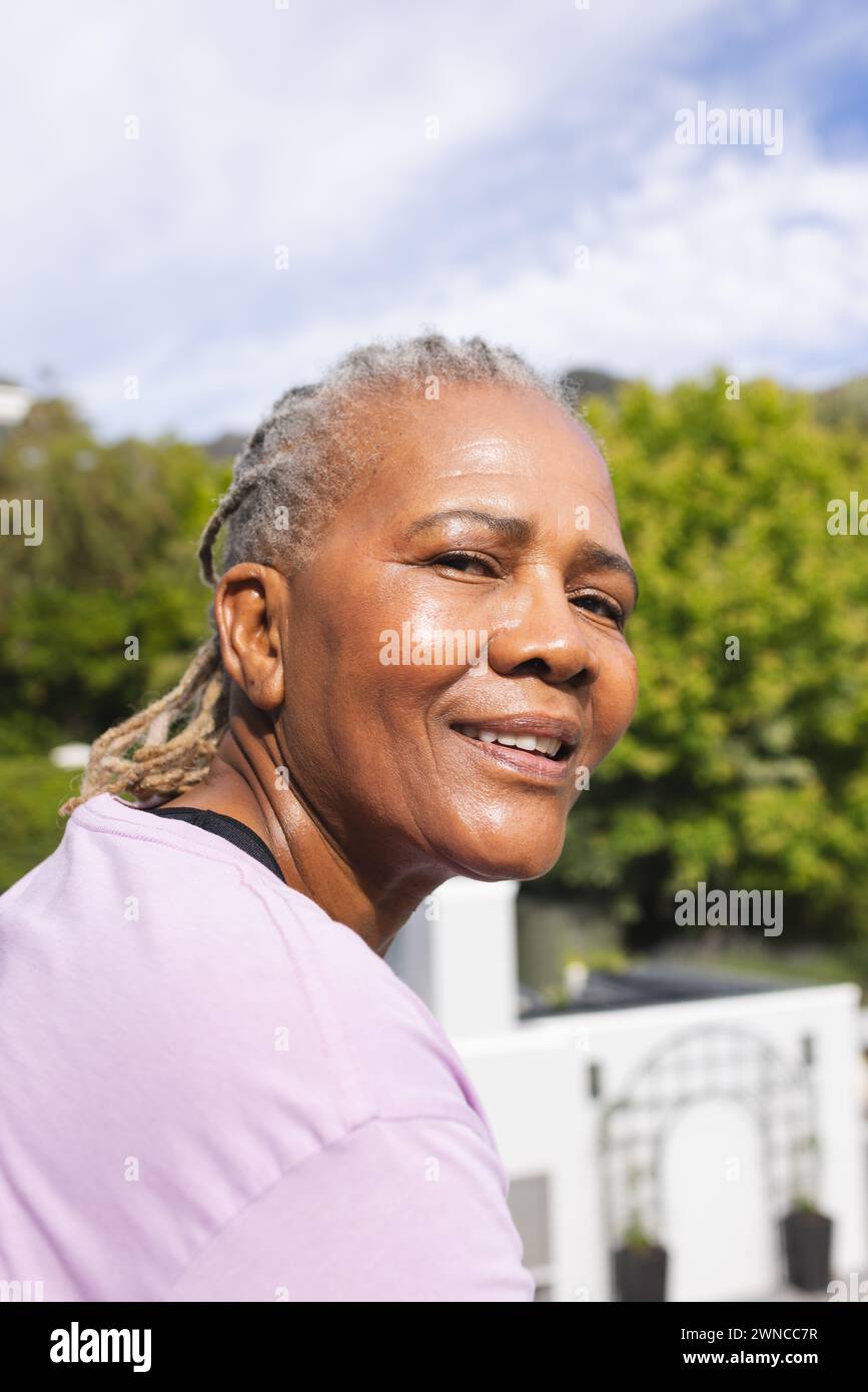 Senior biracial woman with grey hair smiles outdoors Stock Photo