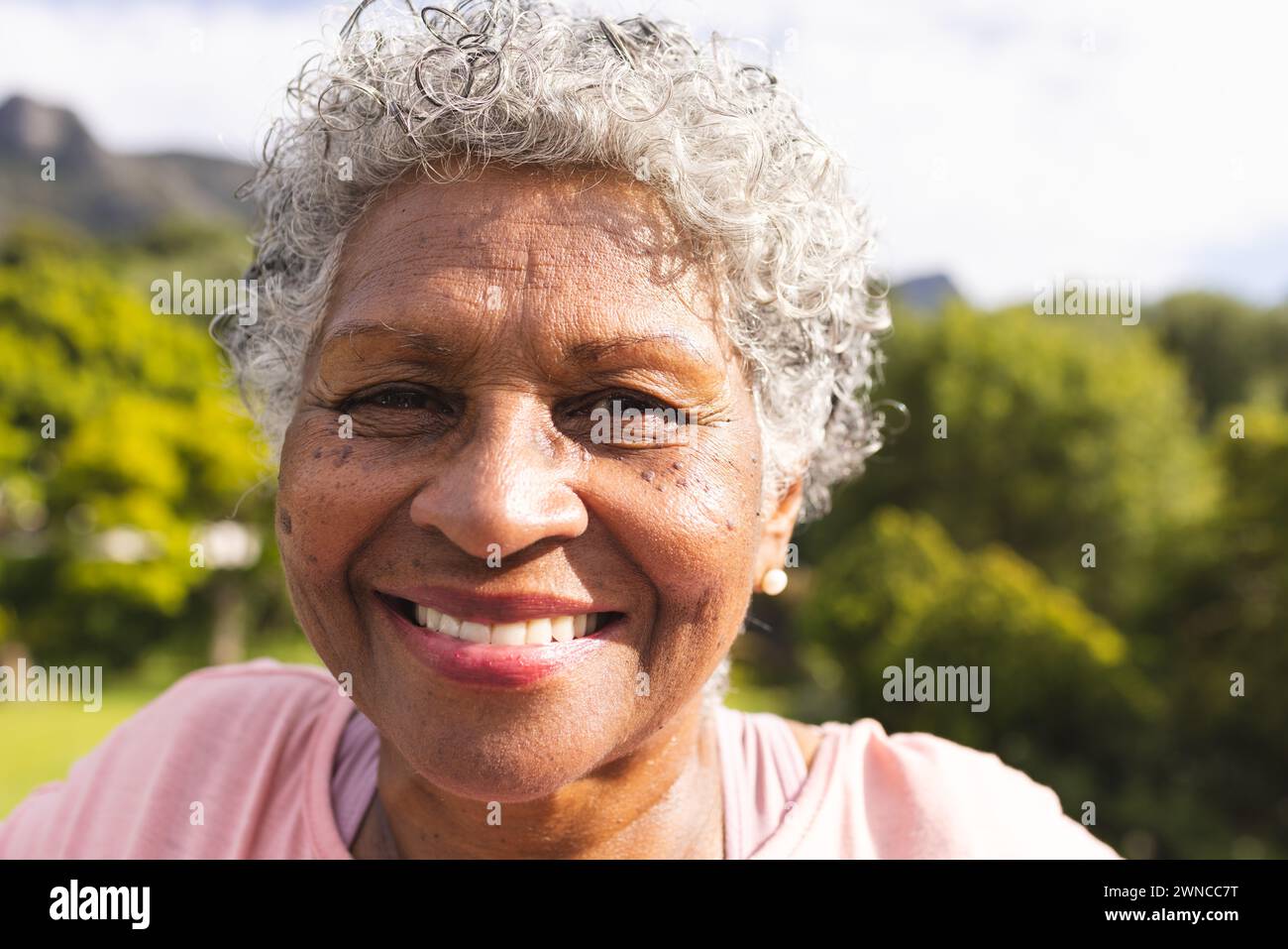 Senior biracial woman with curly gray hair smiles warmly outdoors Stock ...