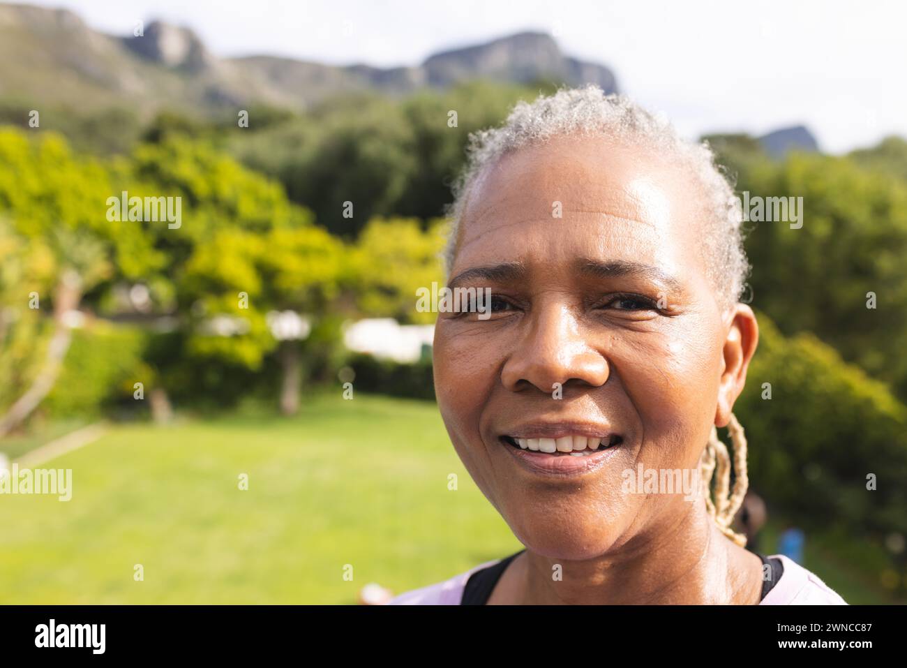 Senior biracial woman with grey hair smiles outdoors with copy space Stock Photo