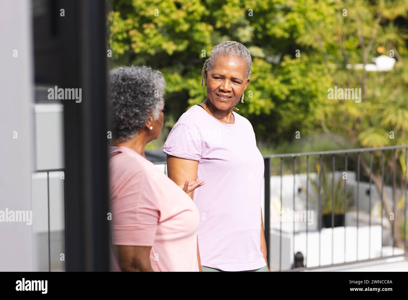 Senior African American woman converses with a senior biracial woman on a sunny balcony Stock Photo