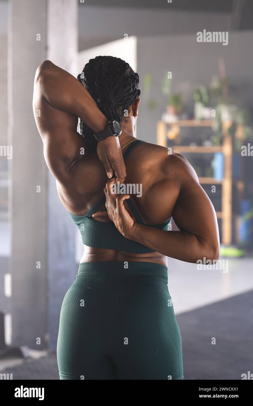 Strong biracial woman stretches her arm behind her head, wearing a green sports outfit Stock Photo