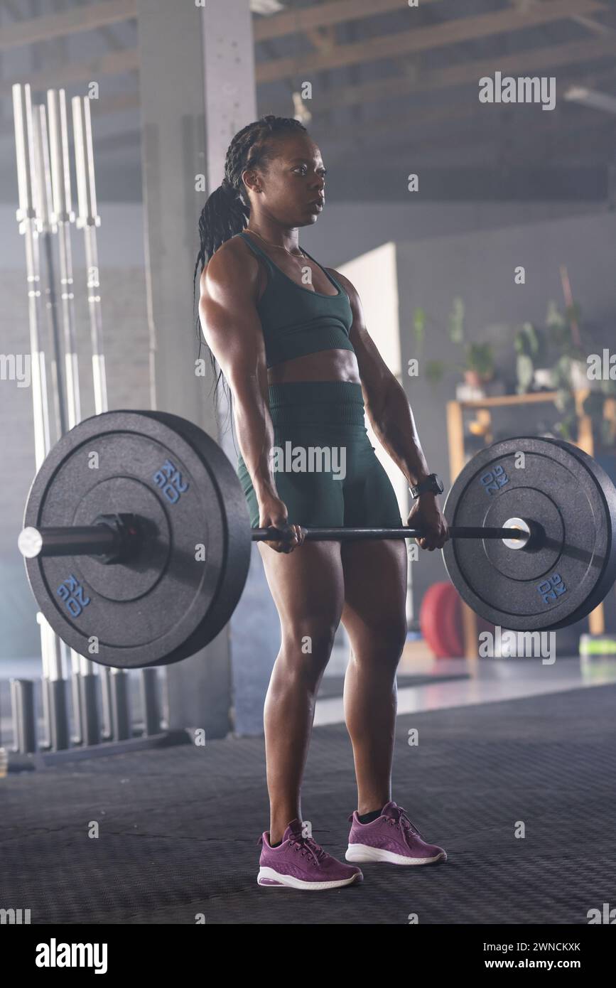 Strong biracial woman lifts weights at a gym, showcasing strength and determination with copy space Stock Photo