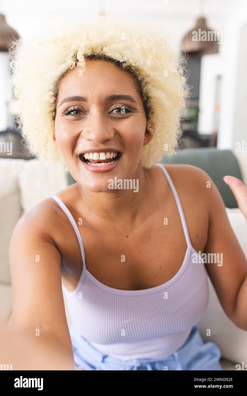 Young biracial woman with curly blonde hair smiles at the camera on ...