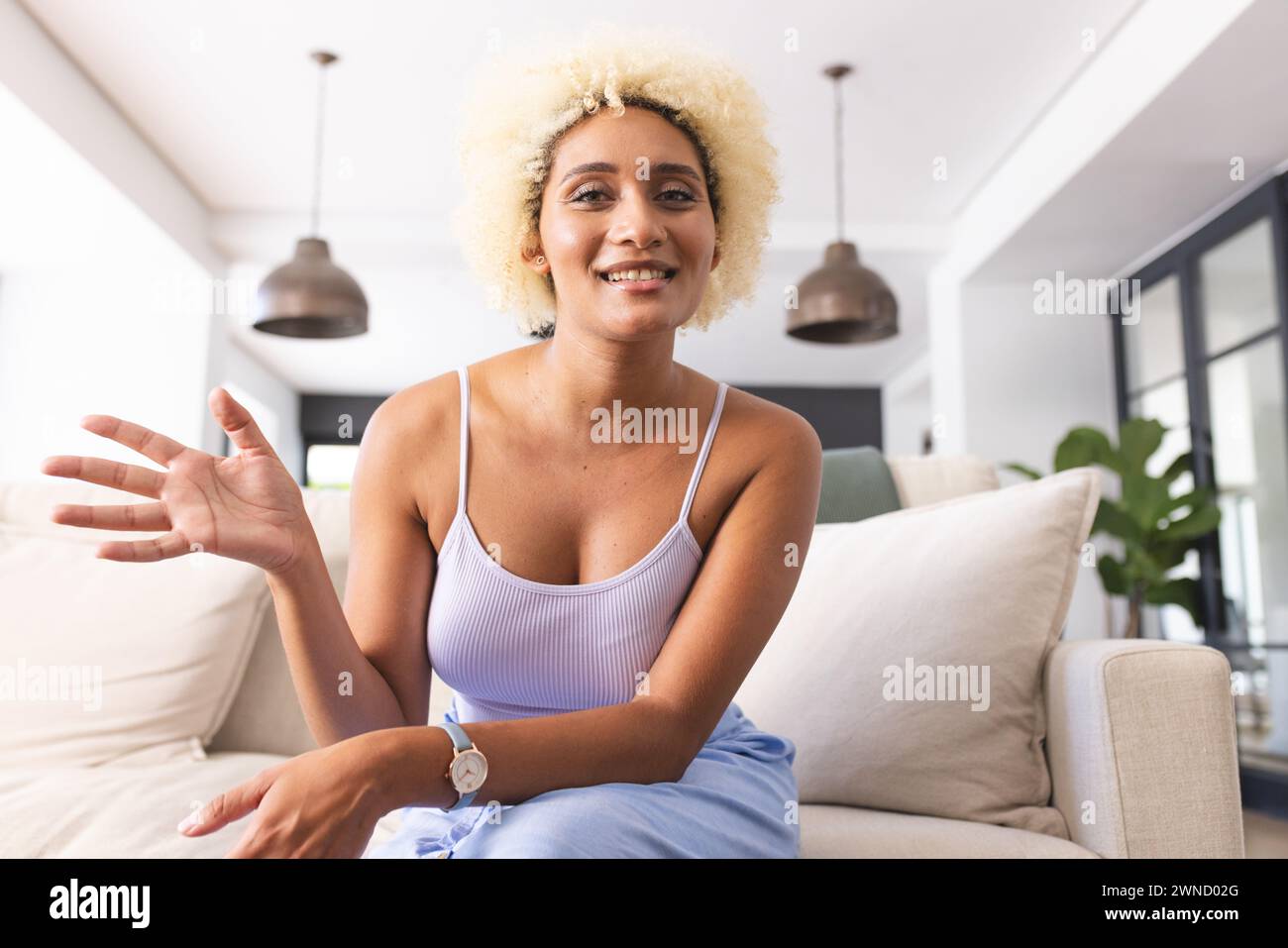 Young biracial woman with curly blonde hair smiles while gesturing on ...