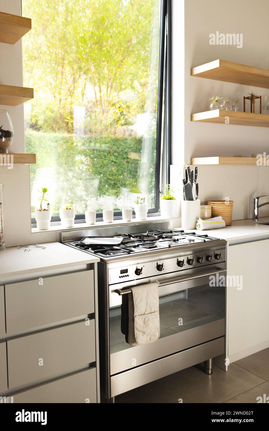 A modern kitchen features a stainless steel stove and white countertops with copy space Stock Photo