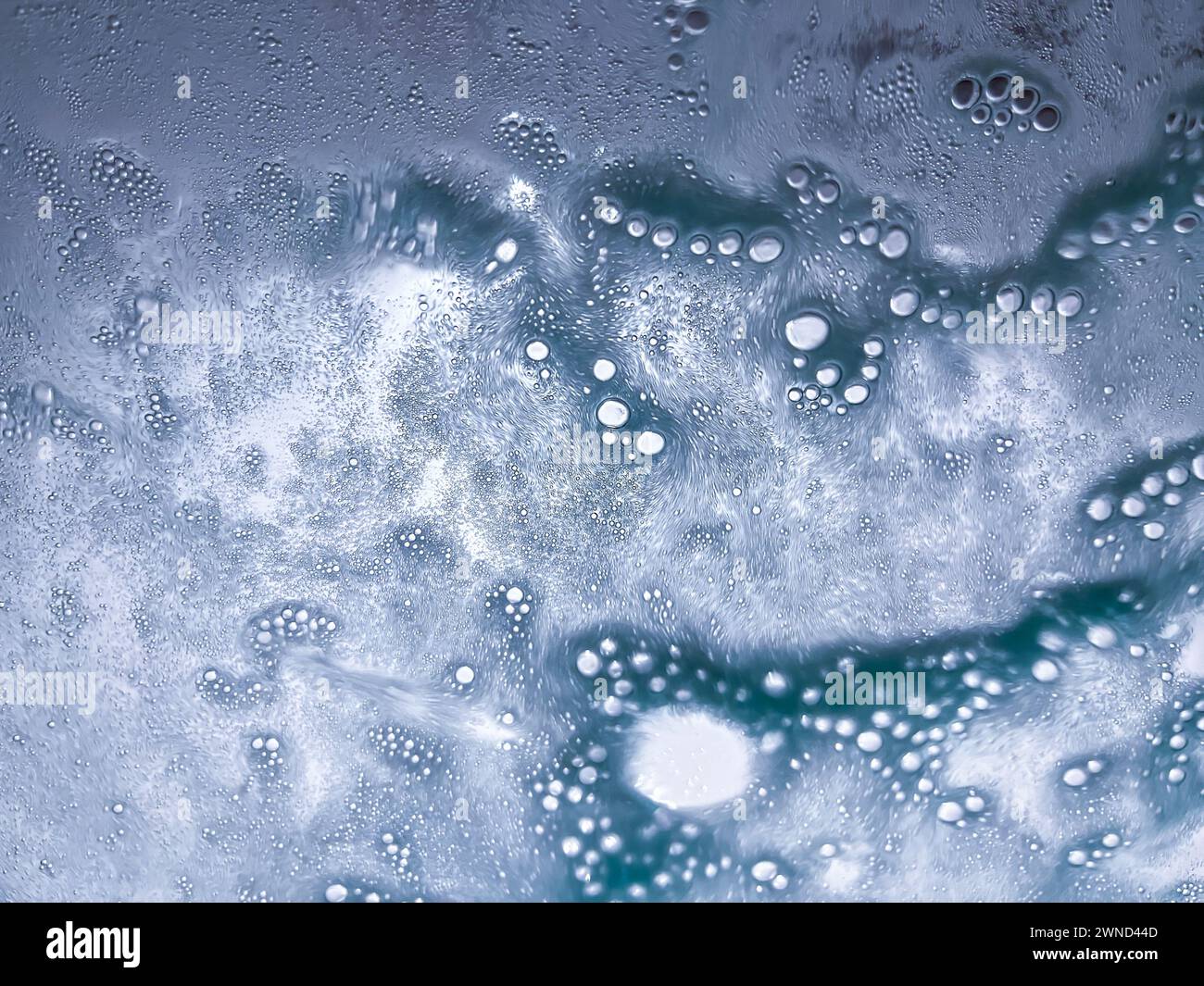 Abstract texture background of water and suds spraying on the windshield of a vehicle in an automated car wash Stock Photo