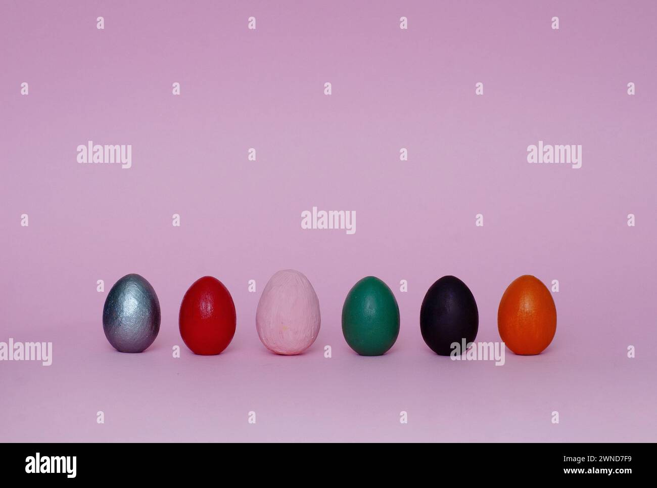 Six assorted ornamental hand painted eggs stand on paper background. Easter composition. Stock Photo