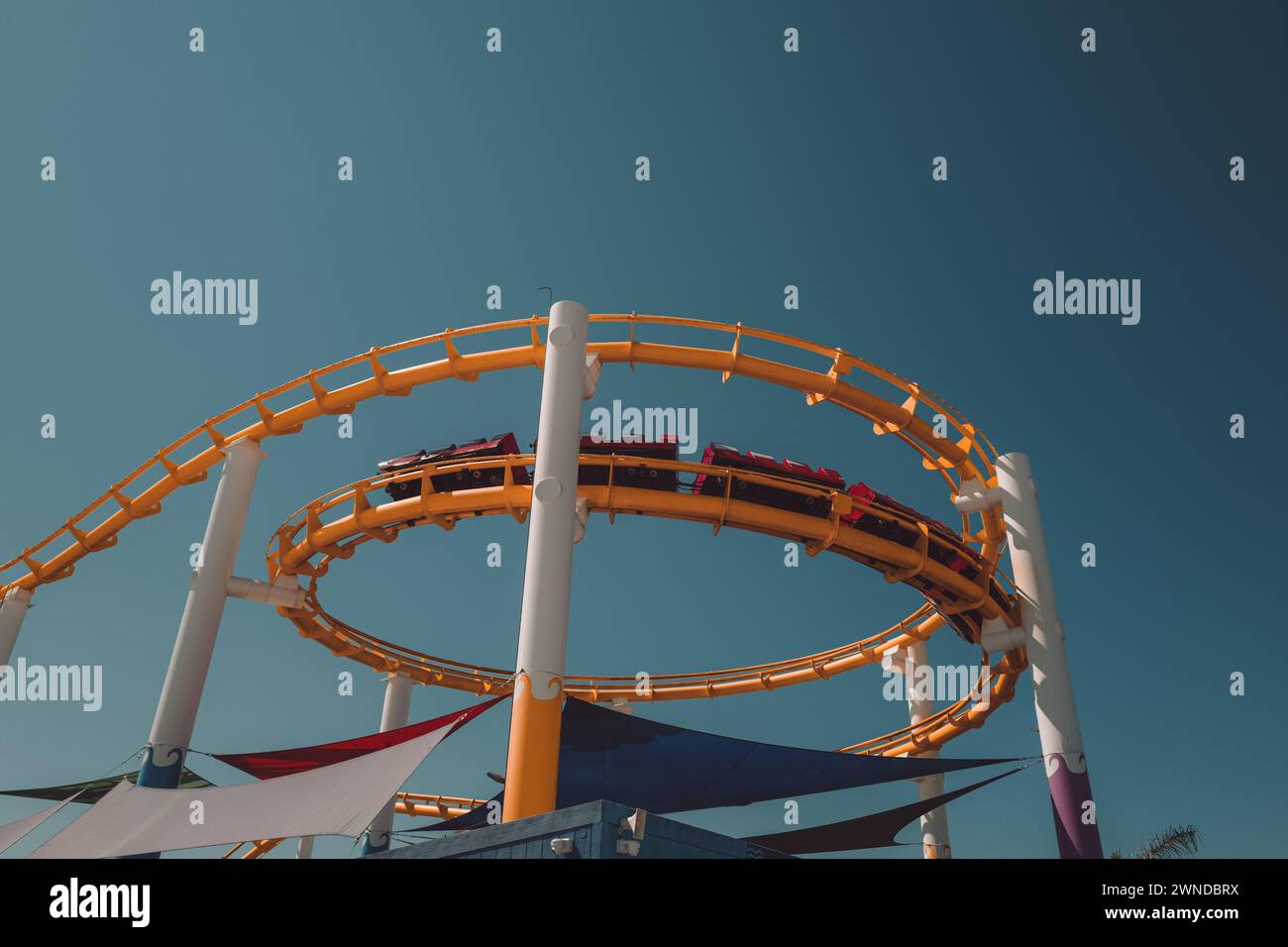 Moving roller coaster in an amusement park during the summer daytime. Entertainment, fun and activity Stock Photo