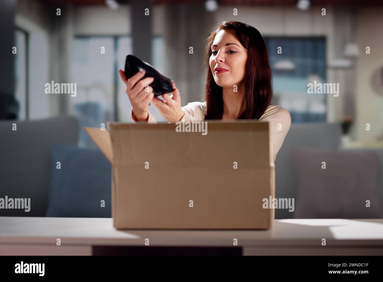 Smiling Young Woman Sitting On Sofa Unpacking Received Parcel Stock Photo