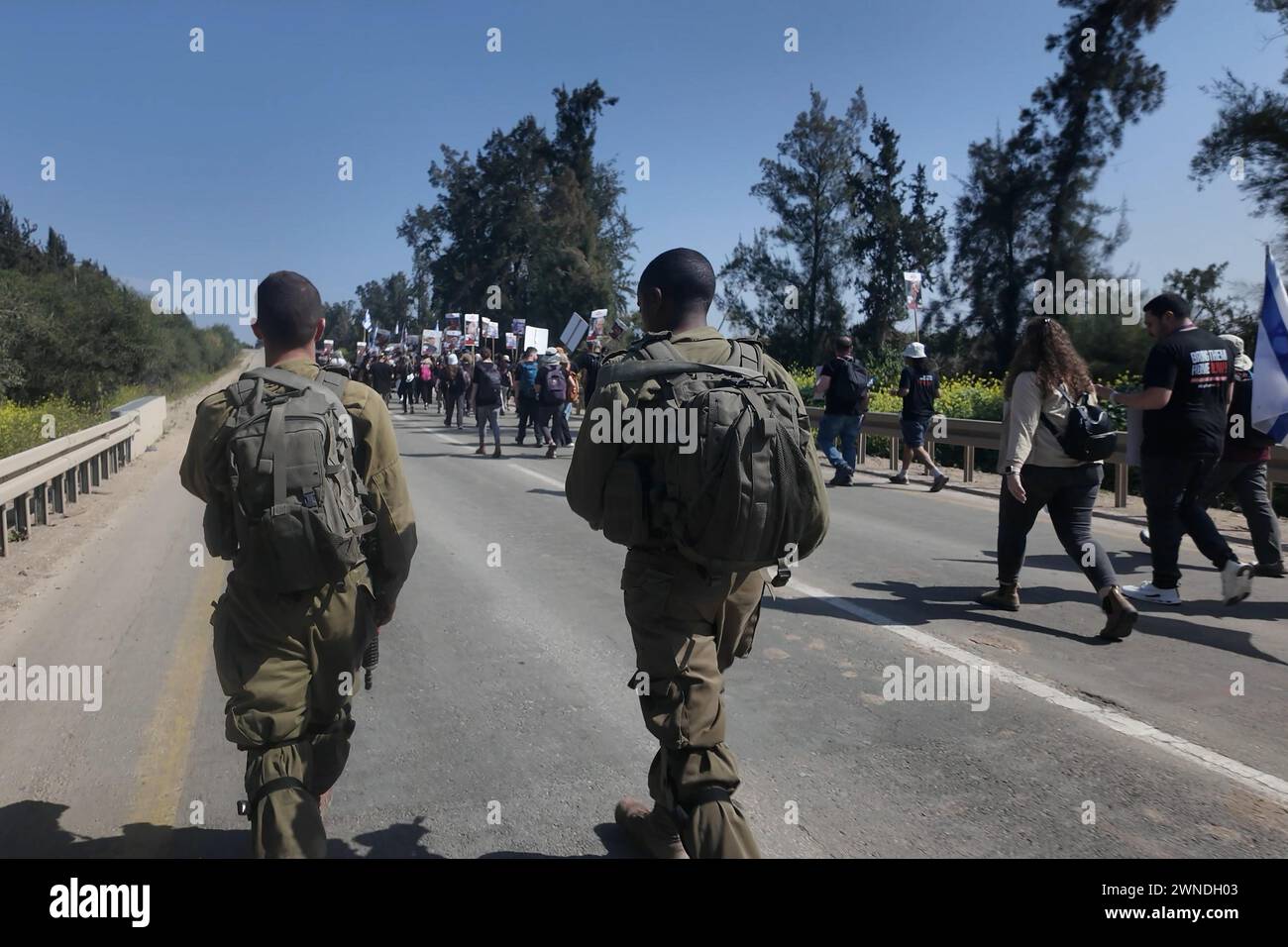 Israeli soldiers secure families of hostages held in Gaza and their supporters as they start a four-day protest march from the Supernova massacre site to Jerusalem, calling for the release of the hostages held by Hamas on February 28, 2024 in Re'im, Israel. Stock Photo