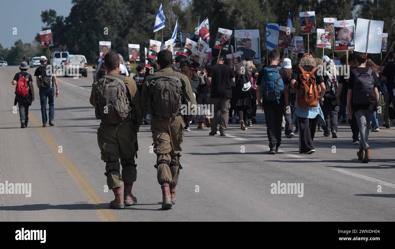 Israeli soldiers secure families of hostages held in Gaza and their supporters as they start a four-day protest march from the Supernova massacre site to Jerusalem, calling for the release of the hostages held by Hamas on February 28, 2024 in Re'im, Israel. Stock Photo