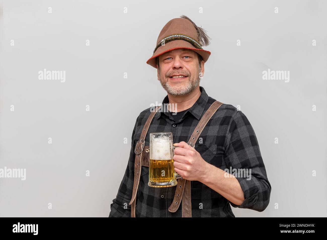 Elderly bearded man in hat wants to drink a glass of beer with foam, beer festival in Austria and Germany. Stock Photo