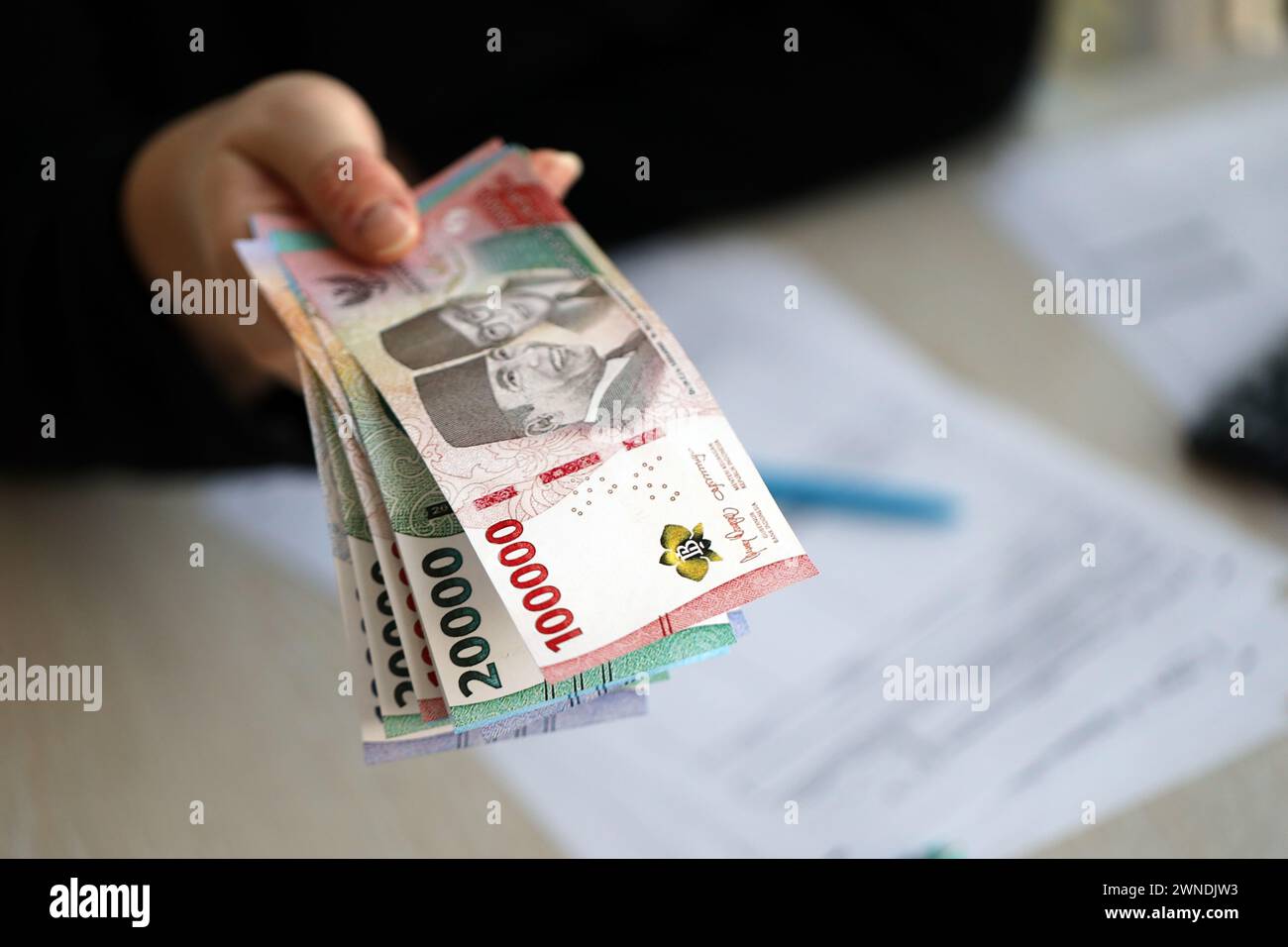 Female accountant hand give bunch of many indonesian rupiah money bills of new series close up Stock Photo