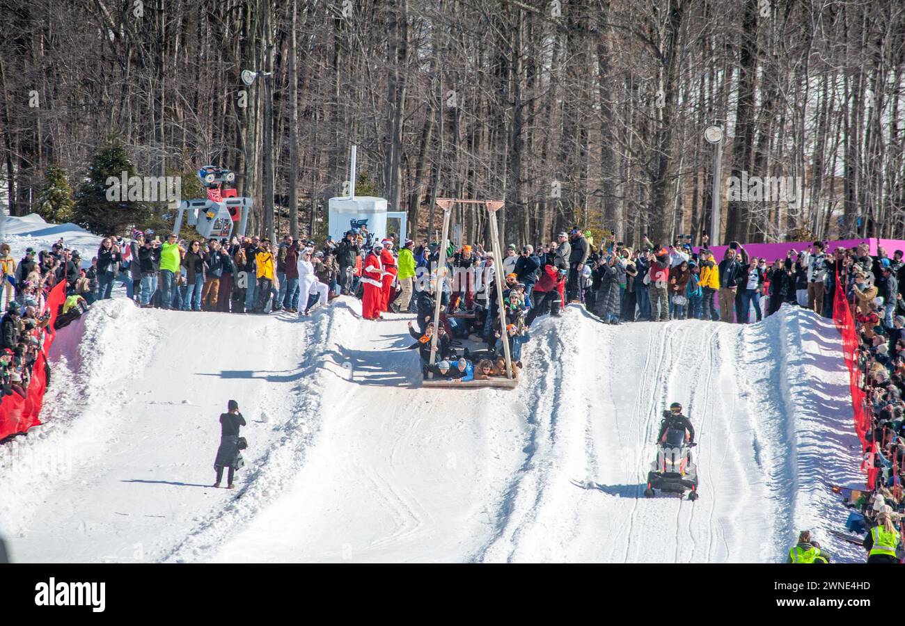 Participants react after sledding down the mountain in their swing themed sled during the 2024
