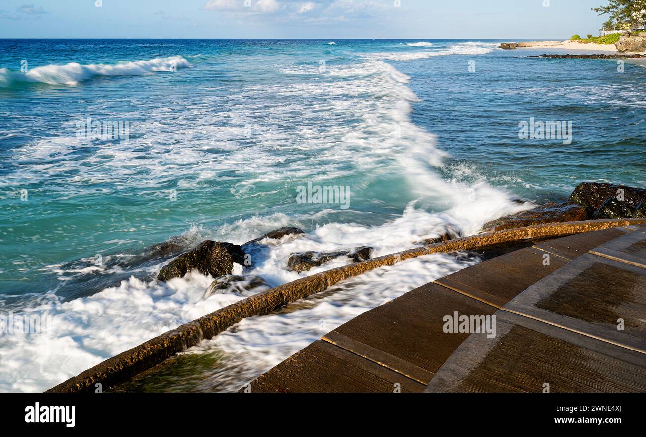 Inviting crystal clear sea and foaming surf gently lapping on the beautiful soft sands of Rockley Beach, Barbados. Stock Photo