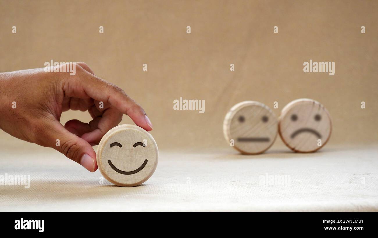Wooden round with carved happy and angry faces, International Day of Happiness concept, customer reviews, emotional intelligence, emotional control ba Stock Photo