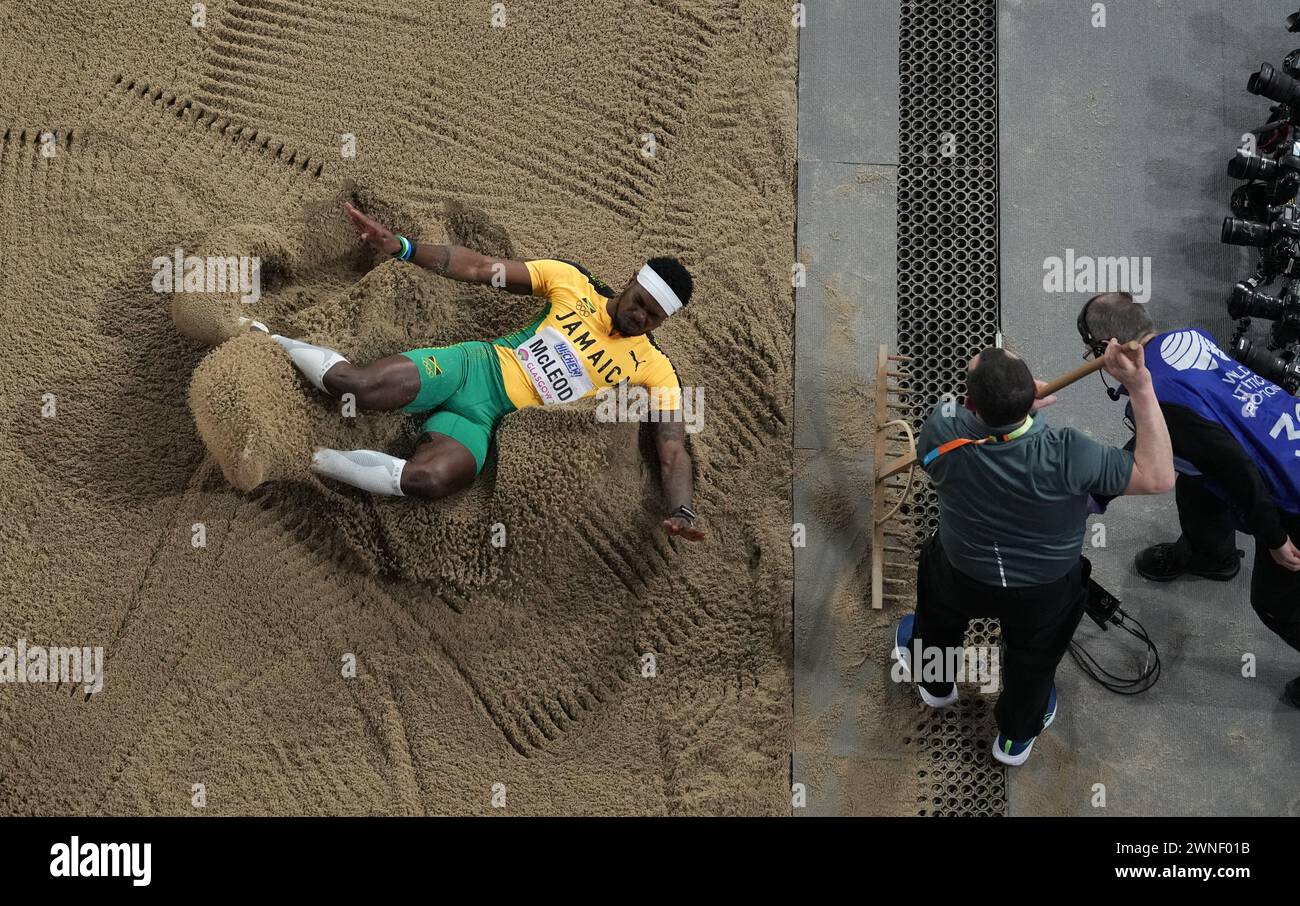 Jamaica's Carey Mcleod lands in the pit as staff rake the sand during