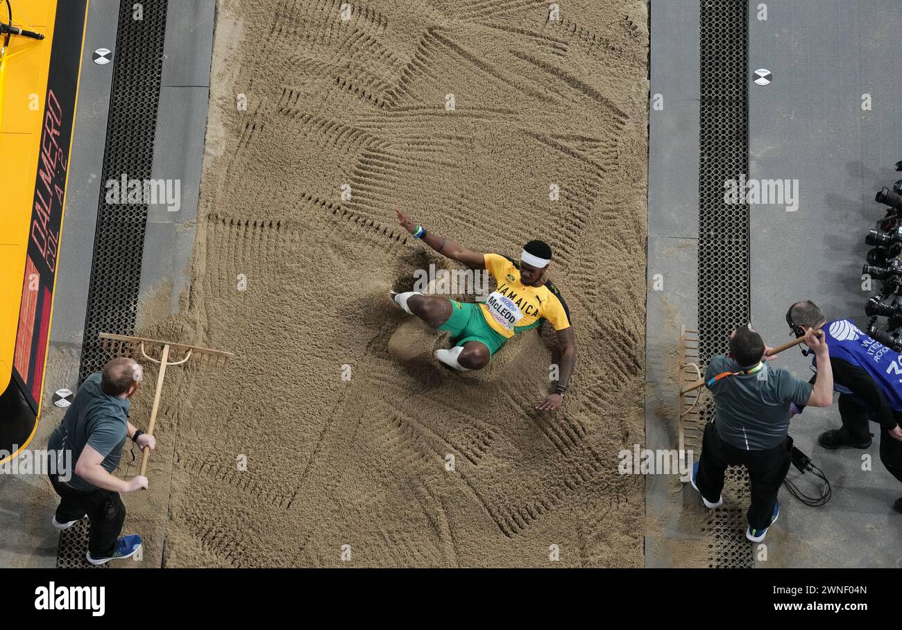 Jamaica's Carey Mcleod lands in the pit as staff rake the sand during