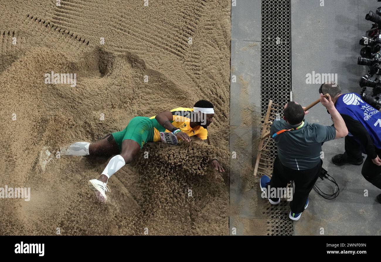Jamaica's Carey Mcleod lands in the pit as staff rake the sand during