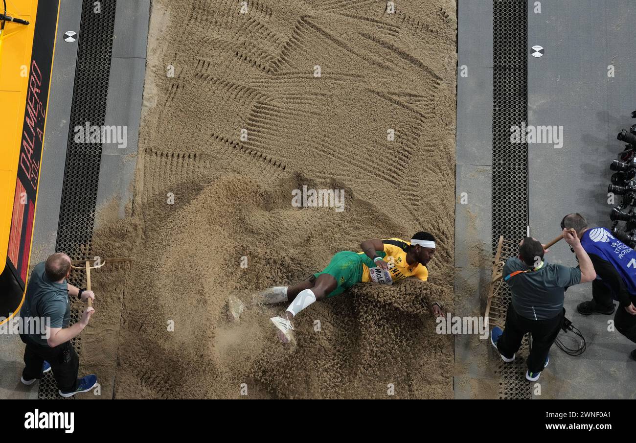 Jamaica's Carey Mcleod lands in the pit as staff rake the sand during