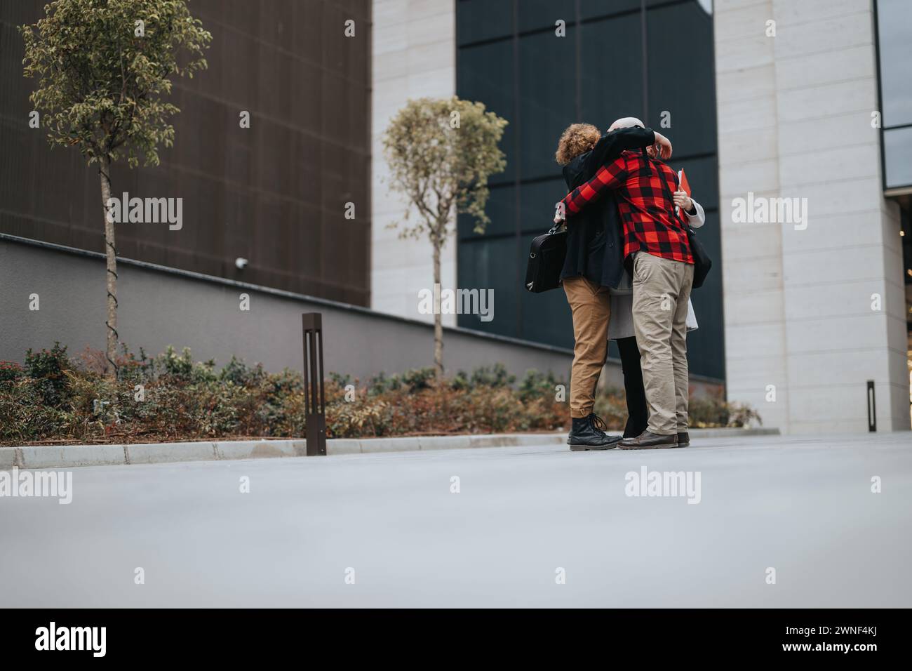 Business partners celebrating success with a hug outside modern office ...