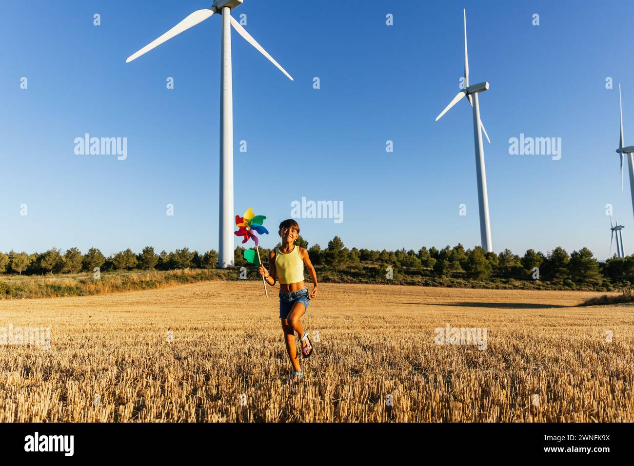 Energetic girl playing with pinwheel in agricultural field Stock Photo ...