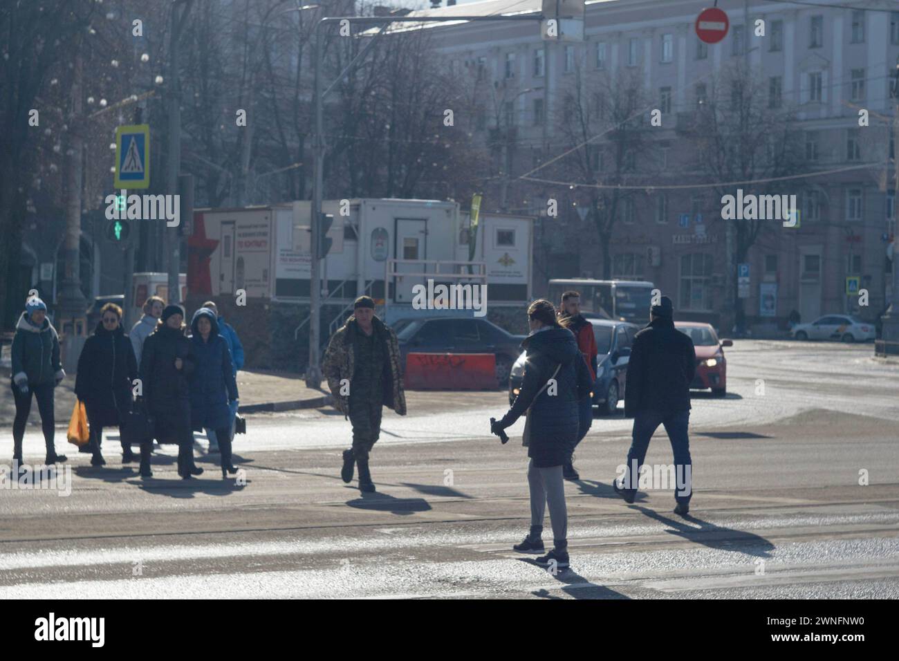March 1, 2024, Voronezh, Russia: Pedestrians cross opposite the railway station and a registration point for military service, At the end of February - beginning of March, spring warmth came to the million-plus city of Central Russia, Voronezh. Slush and puddles did not prevent Voronezh residents from seeing election campaign signs on street boards. The presidential elections in the Russian Federation are scheduled for March 17. Four candidates are participating in the elections, three of whom fully support the policies of the current president, Vladimir Putin. And the fourth is the current pr Stock Photo
