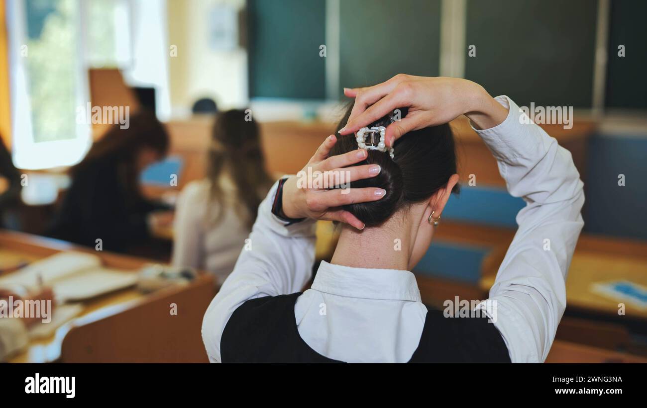 A schoolgirl fixes her hair during class Stock Photo - Alamy