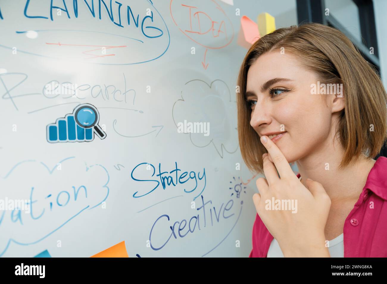 Young beautiful businesswoman putting sticker on glass board while ...
