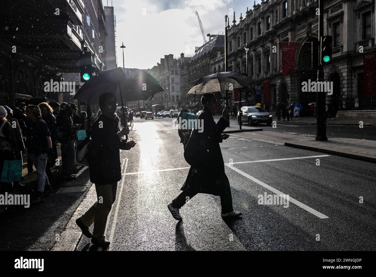 Pedestrians shelter under umbrellas whilst making their way along past Fortnum & Mason department store on Piccadilly during rain showers in London UK Stock Photo