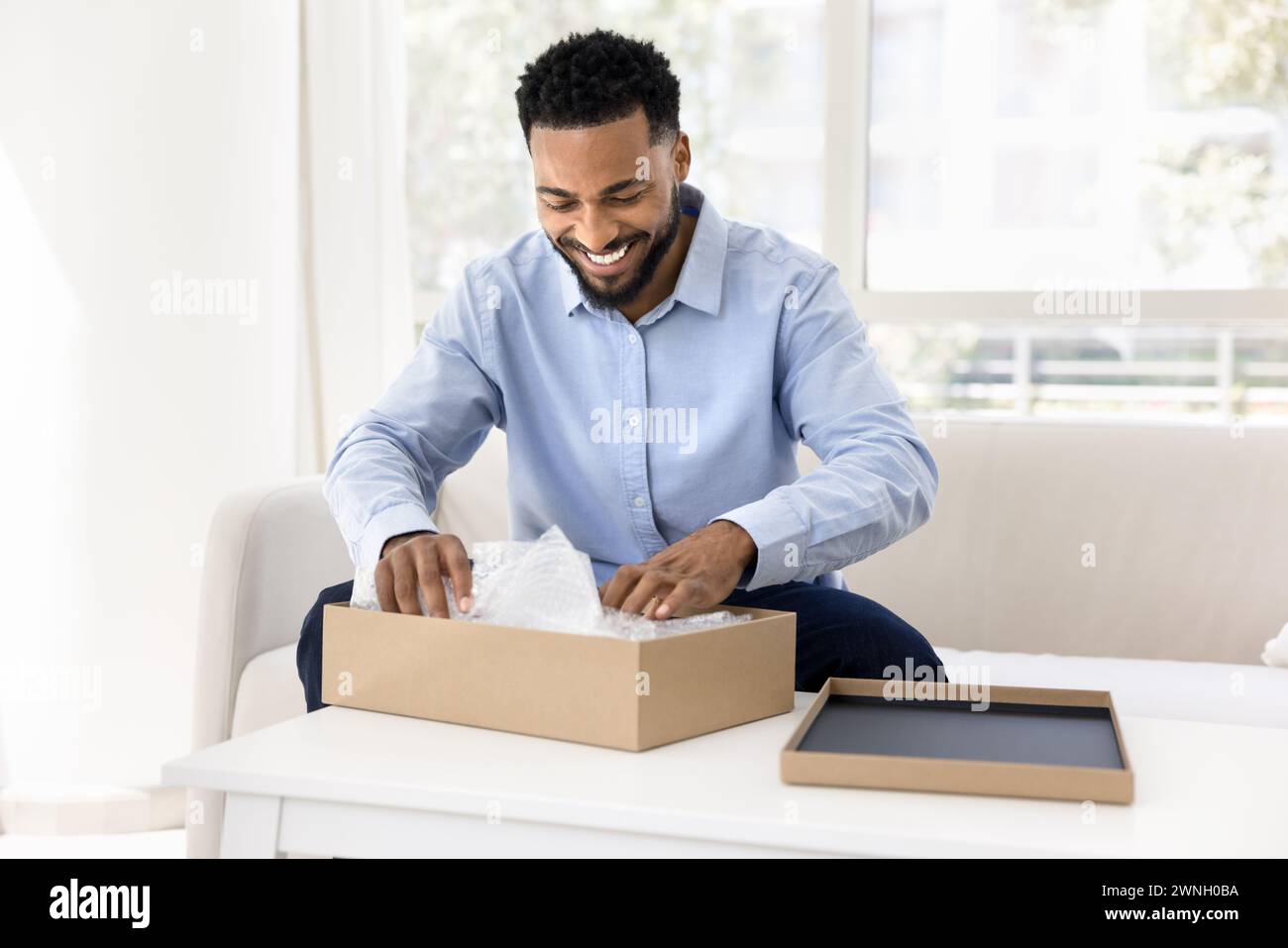 Cheerful young African consumer man getting parcel Stock Photo
