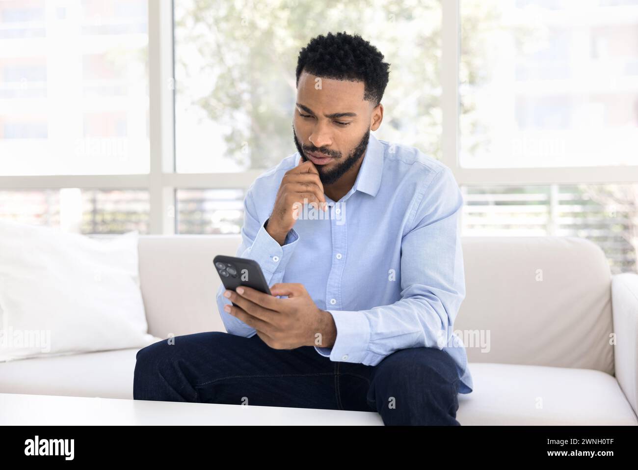 Serious thoughtful young African man using financial service Stock Photo