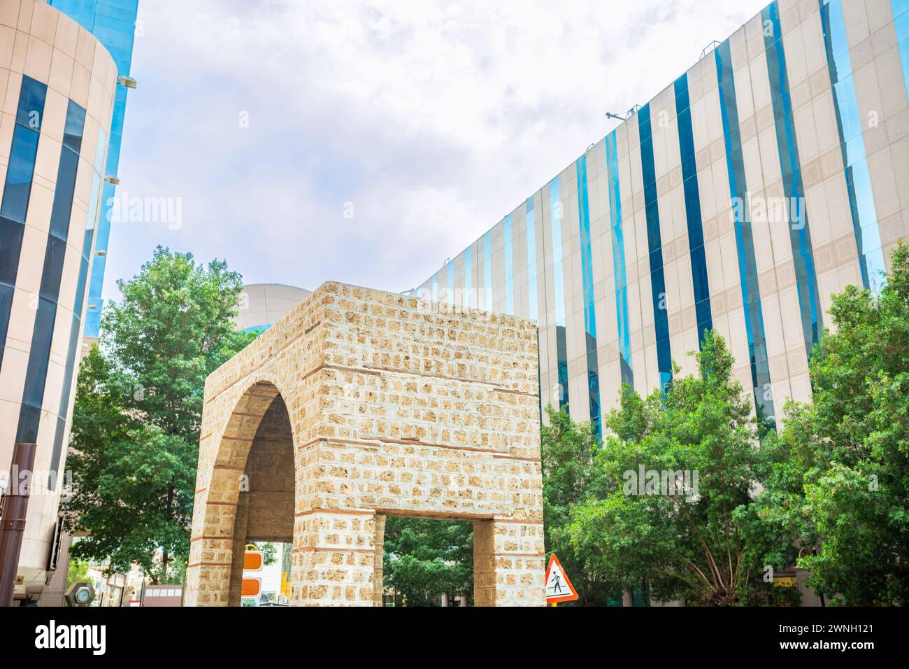 Arch of ancient Bab Alfurdhah Gate surrounded by modern office buildings on the street of Al-Balad, Jeddah, Saudi Arabia Stock Photo