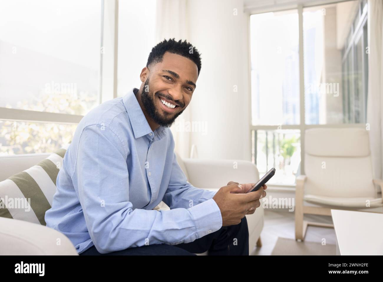 Happy young African American man holding smartphone Stock Photo