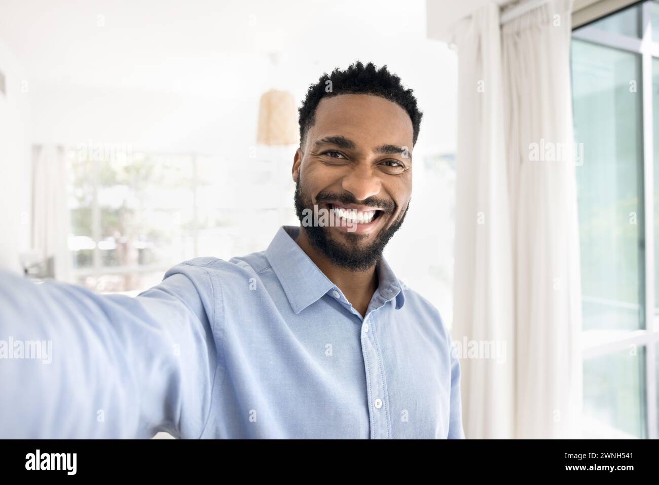 Cheerful handsome young African man taking selfie, looking at camera Stock Photo