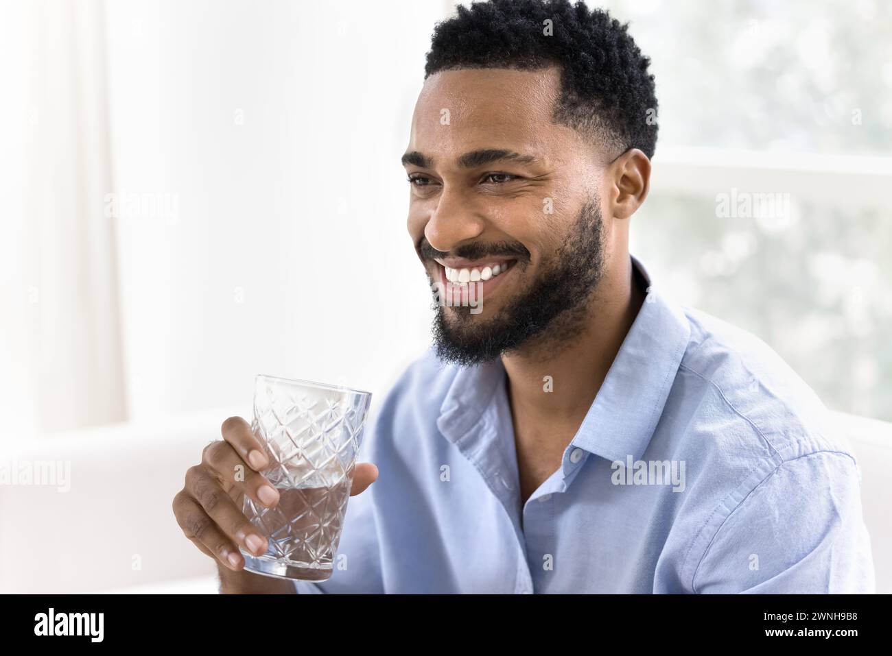 Happy attractive young African man drinking clear pure water Stock Photo