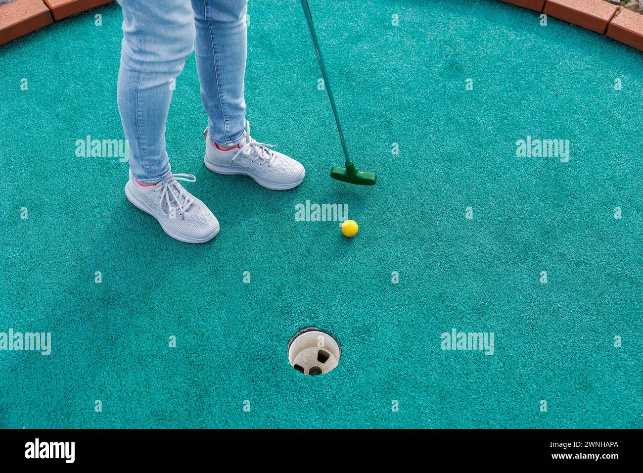 Golfer playing adventure or mini golf and trying putting ball into hole. Sports and leisure activity Stock Photo
