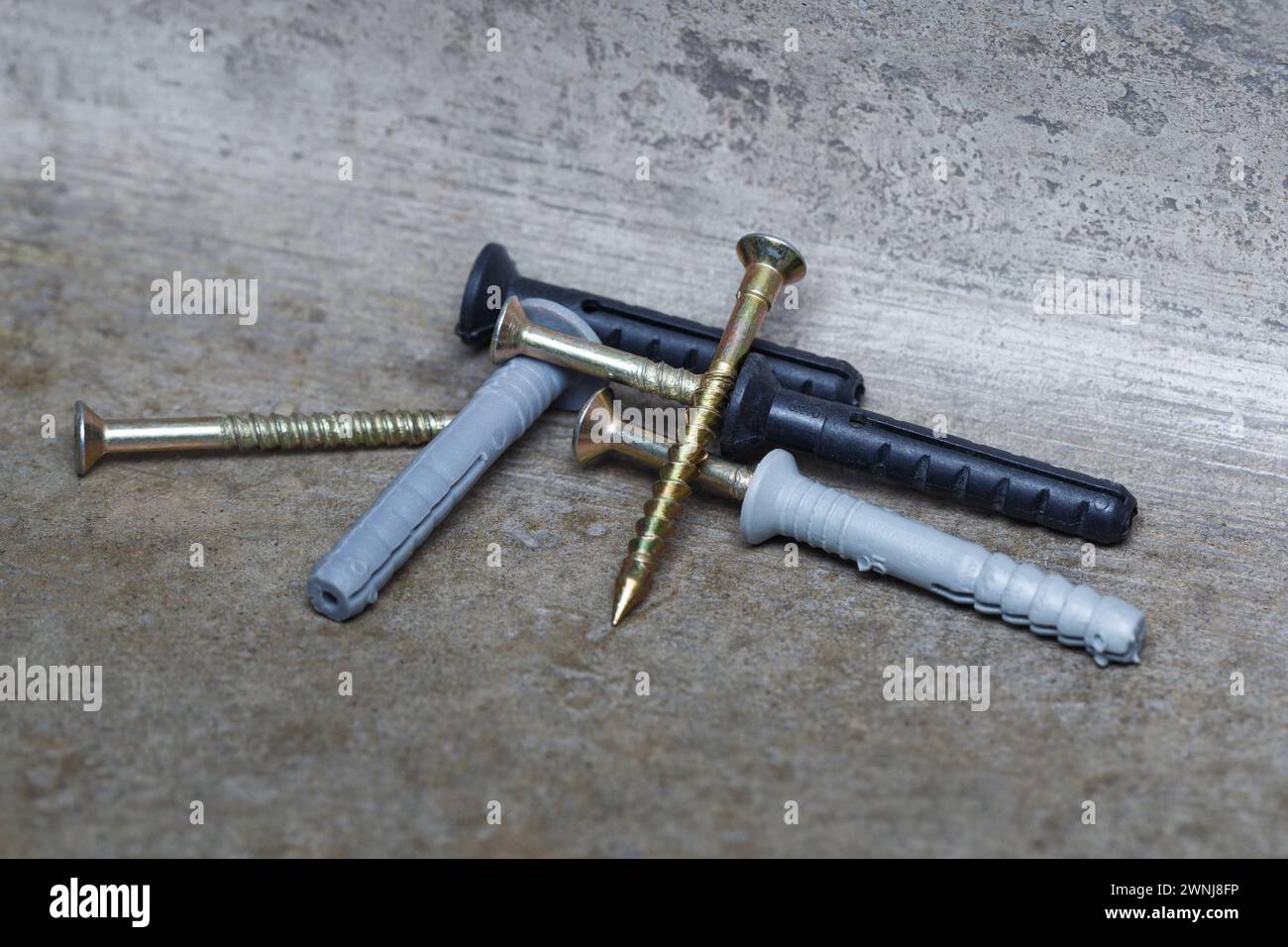 Gray and black dowel nails are scattered on the concrete base. Close-up. Stock Photo