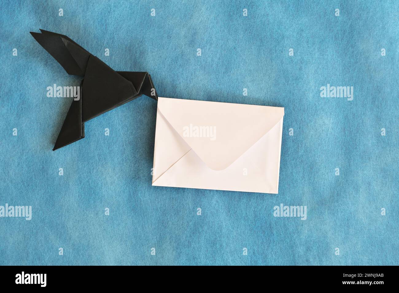 Black raven paper origami carrying white letter envelope. Email ...