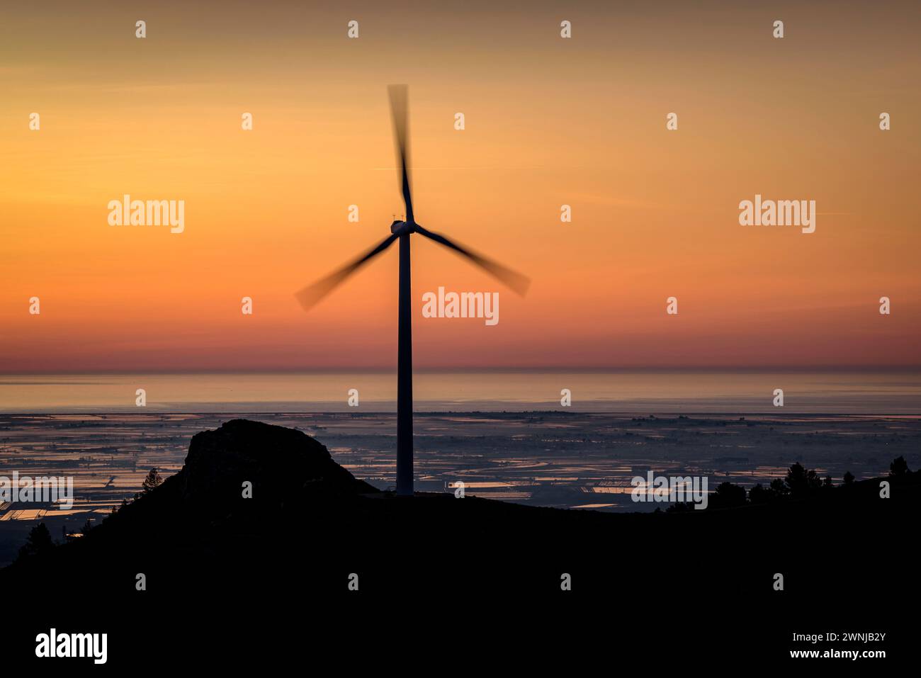 Windmill of the wind farm at sunrise. In the background, the Ebro Delta (Tarragona, Catalonia, Spain) ESP: Molino de viento del parque eólico Stock Photo