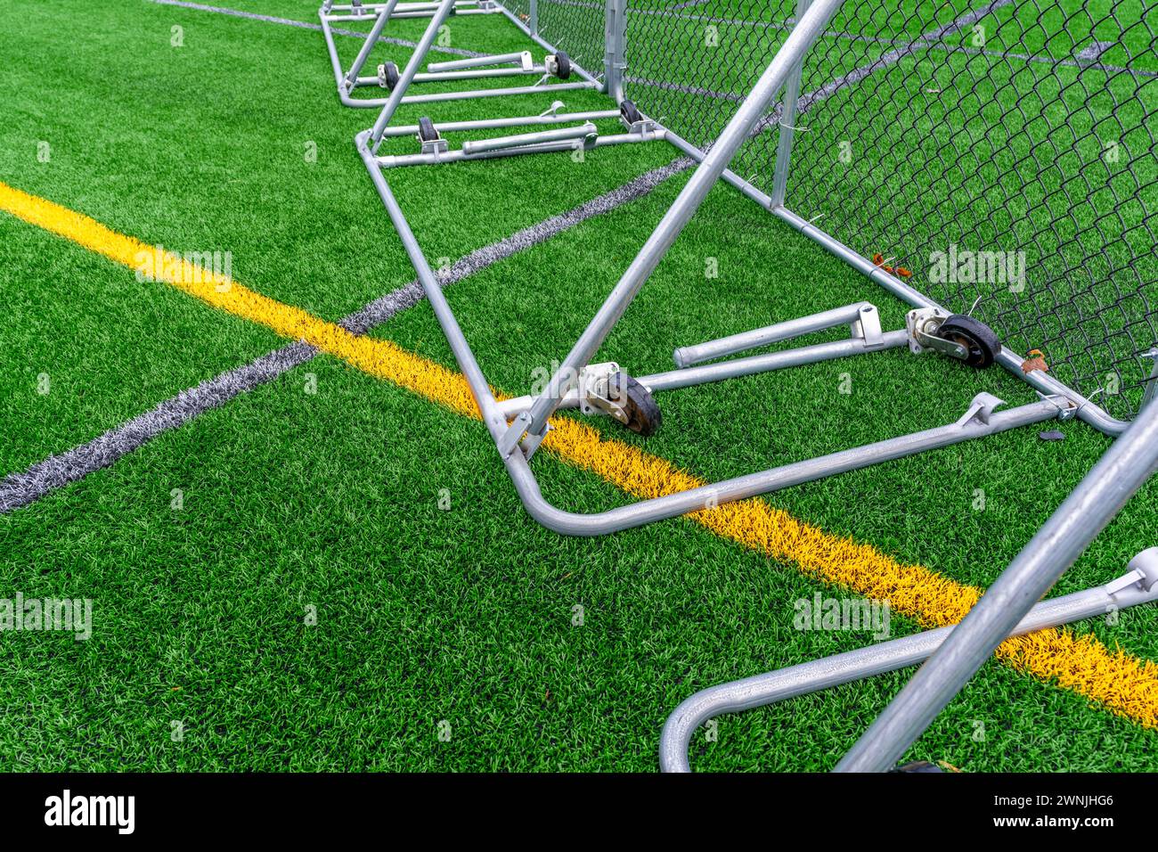 Portable softball baseball outfield fence with red fence cap on a synthetic turf football Stock Photo