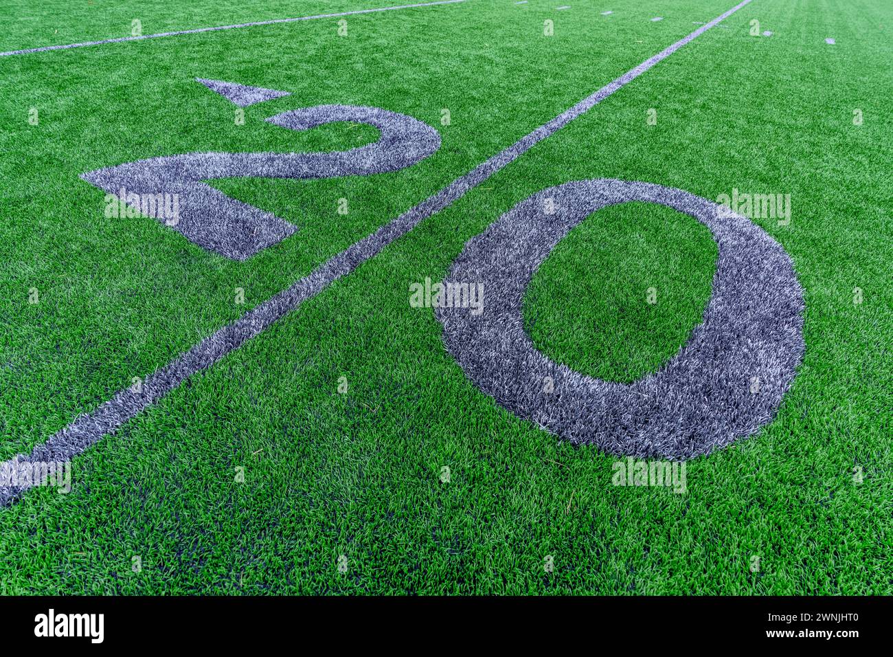 Synthetic turf football 20 yard line and block style numbers in gray.  Practice football turf markings are less obvious and installed in the outfield Stock Photo