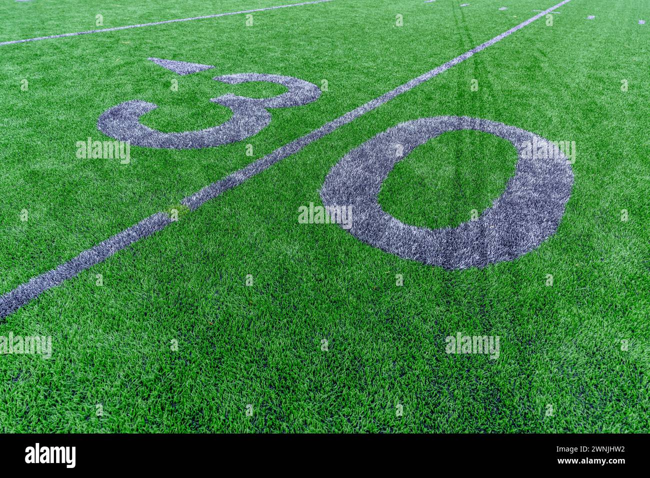 Synthetic turf football 30 yard line and block style numbers in gray.  Practice football turf markings are less obvious and installed in the outfield Stock Photo
