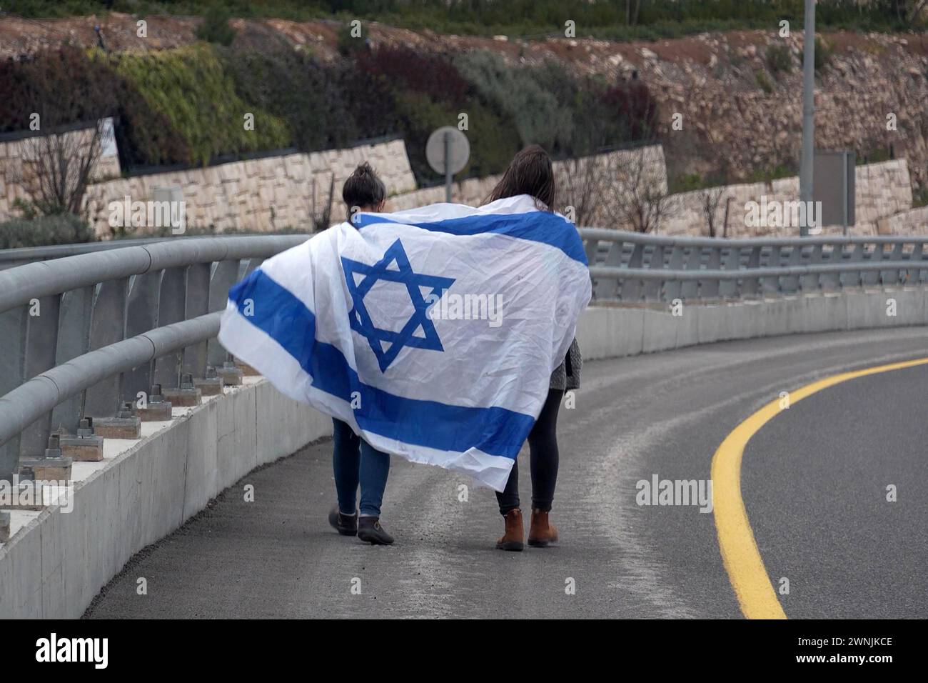 People wrapped with the Israeli flag walk on their way to join a march held by families of Israeli hostages held in Gaza, arriving in Jerusalem for a demonstration near the official residence of Prime Minister, calling for the release of hostages on March 2, 2024 in Jerusalem. Israel Stock Photo