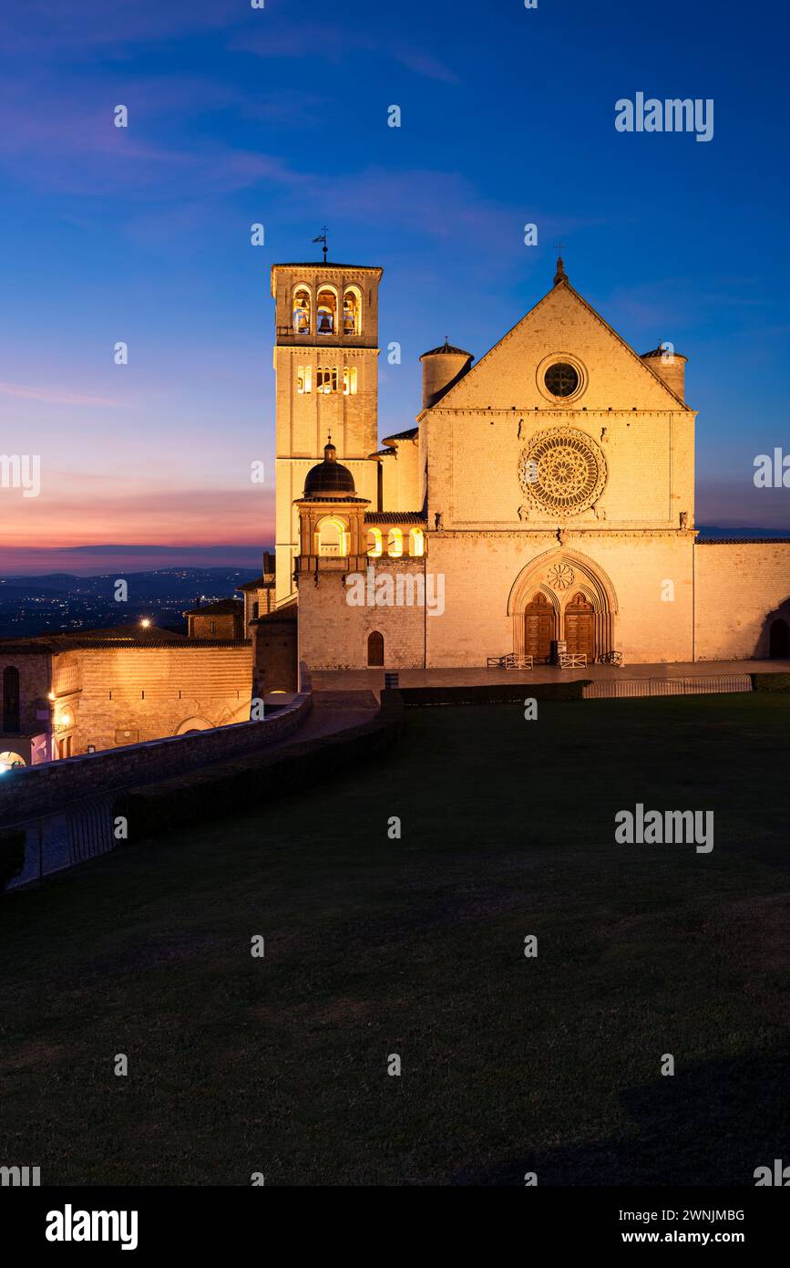 Die beleuchtete Basilika des Hl. Franziskus von Assisi im Zwielicht der Abenddämmerung, Umbrien, Italien Stock Photo