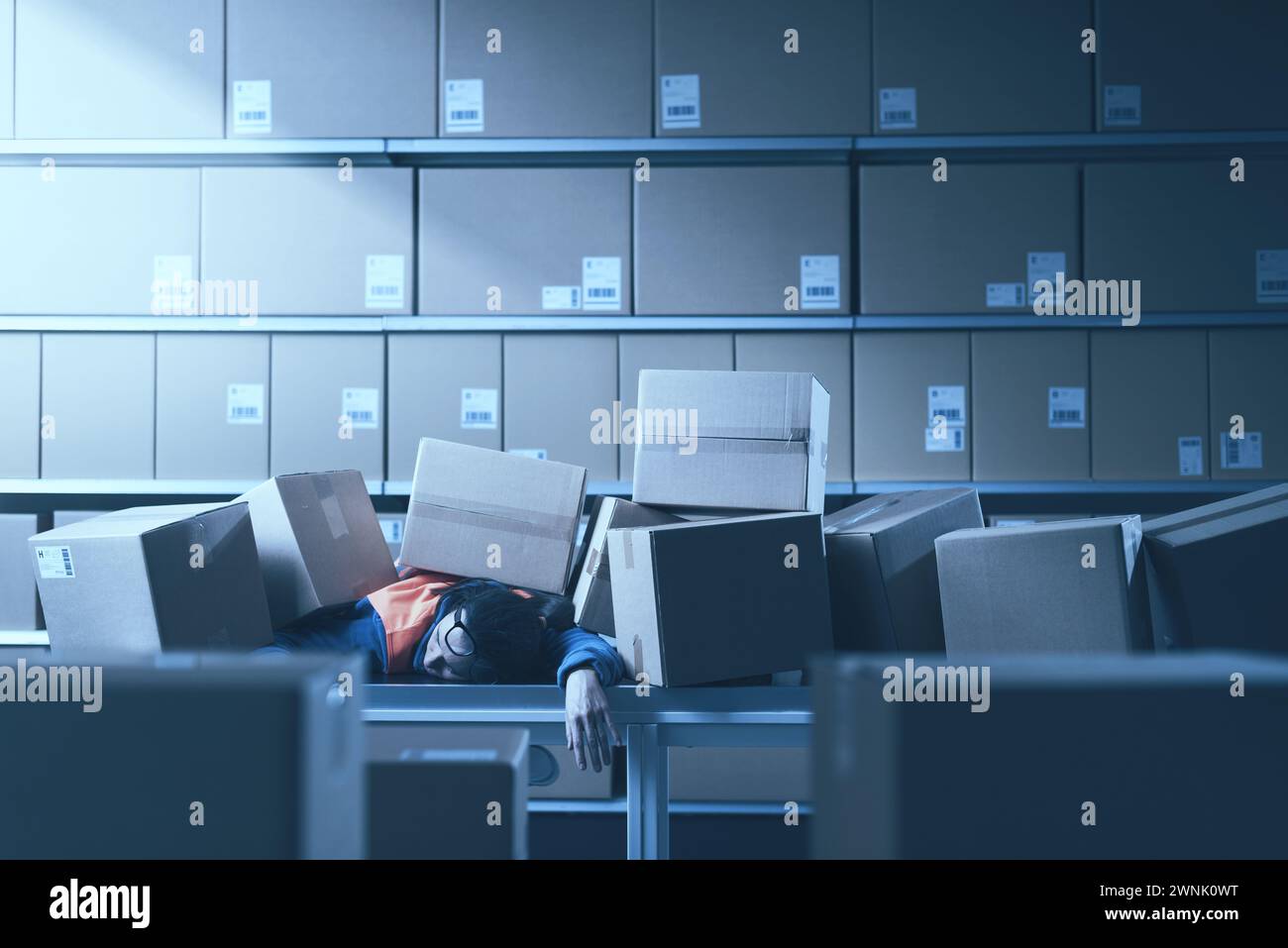 Injured warehouse worker lying under heavy boxes, accidents in the workplace concept Stock Photo