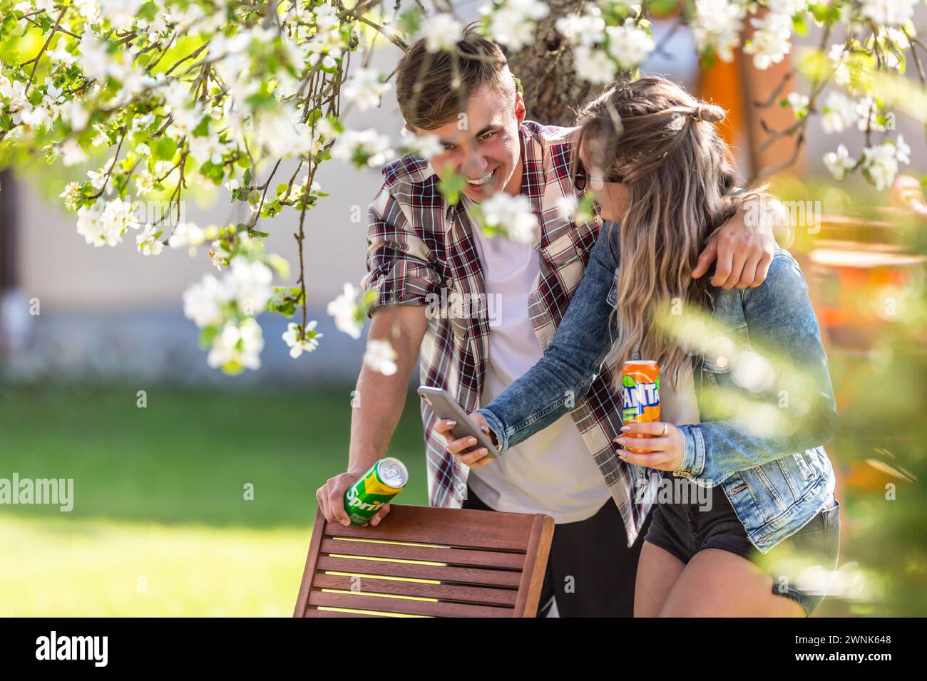 March. 02. 2024 Liptovsky Mikulas. Slovakia - Youth teenagers with cans of Fanta and Sprite are having a laugh under the blooming tree in the garden Stock Photo