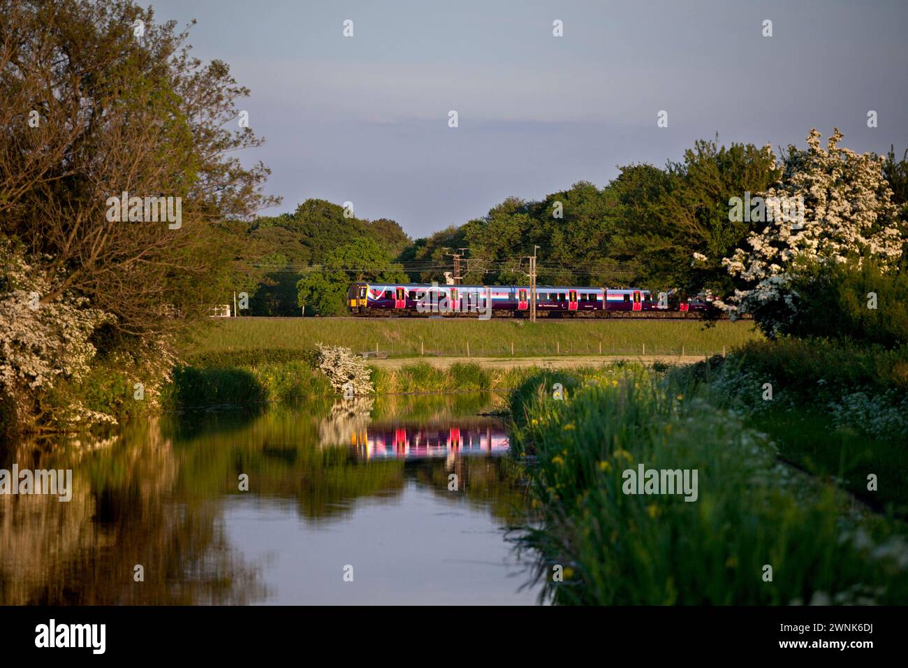 First Transpennine Express class 350 Desiro electri train on the electrified west coast mainline reflected in the canal at Catterall, Lancashire Stock Photo