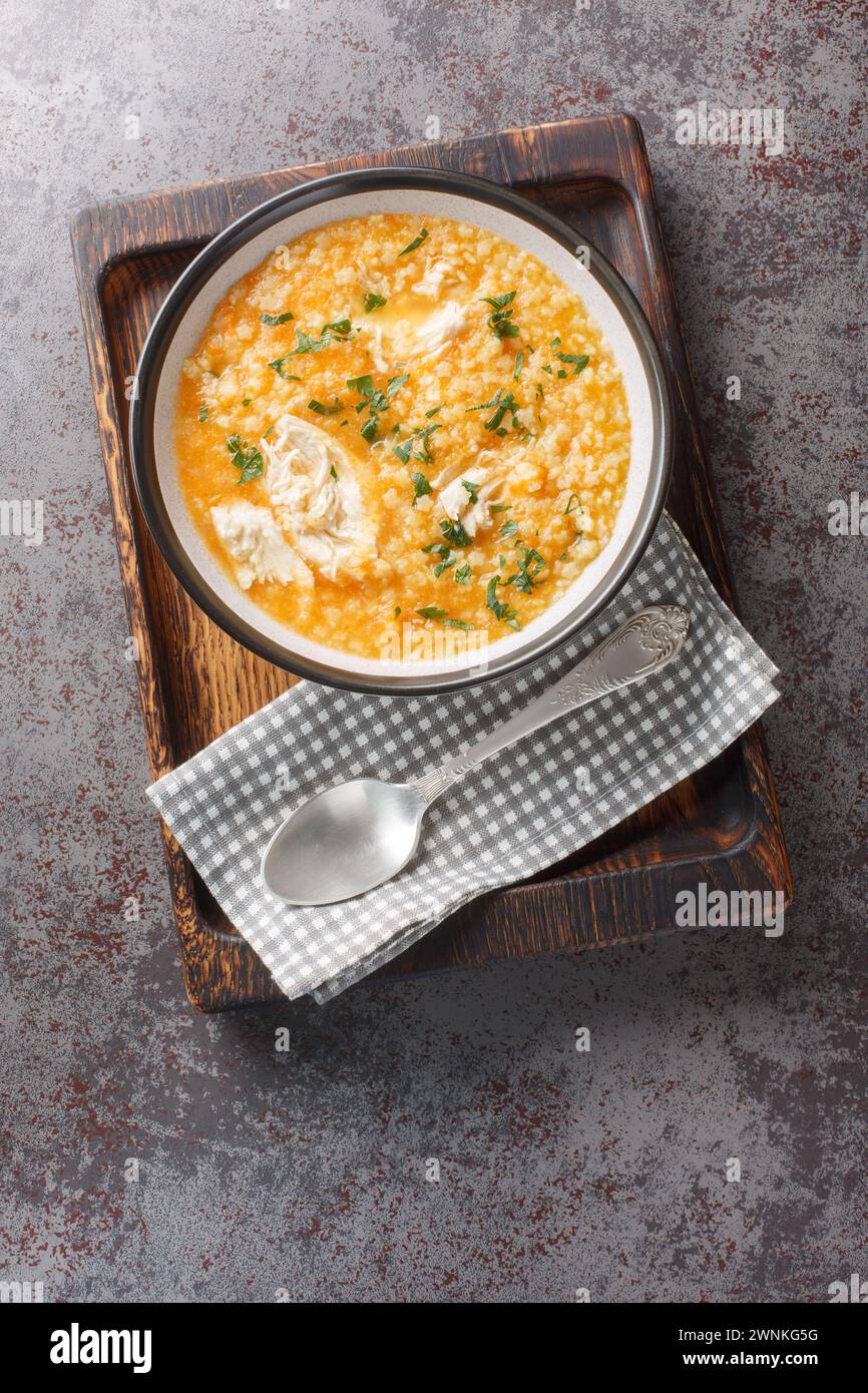 Italian pastina soup with chicken, vegetables and cheese close-up in a bowl on a wooden board. Vertical top view from above Stock Photo